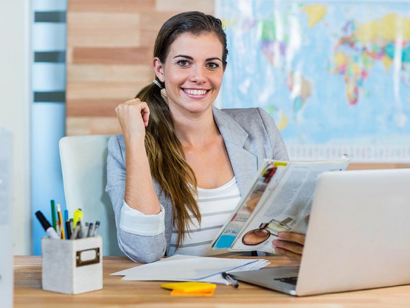Image of Professional Girl with Magazine & Laptop Map in Background