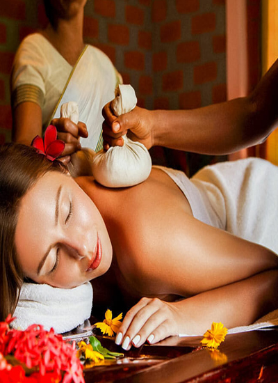 Image of girl taking Ayurvedic Massage with some yellow & Red Flowers 